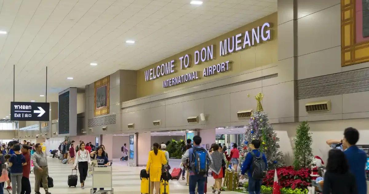 Arrivals hall at Don Mueang International Airport with the welcome sign and passengers with trolleys