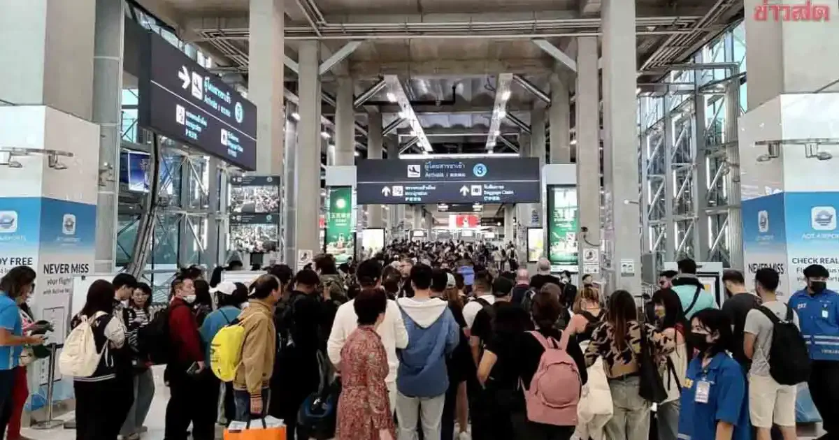 A long queue of arriving passengers with luggage walking towards immigration at Suvarnabhumi Airport
